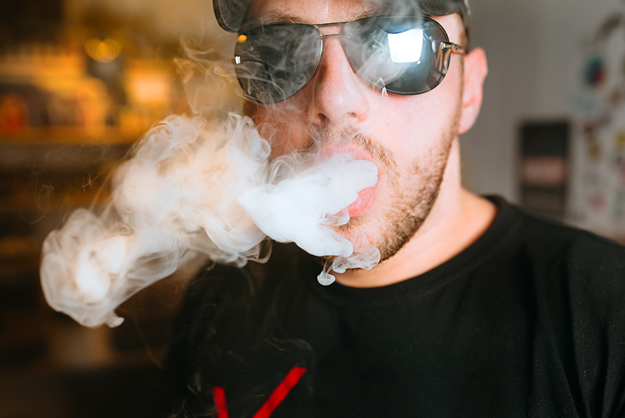 Man with sunglasses exhaling smoke after using live resin cannabis concentrate from Chronic Farms online dispensary Canada. Buy weed online.